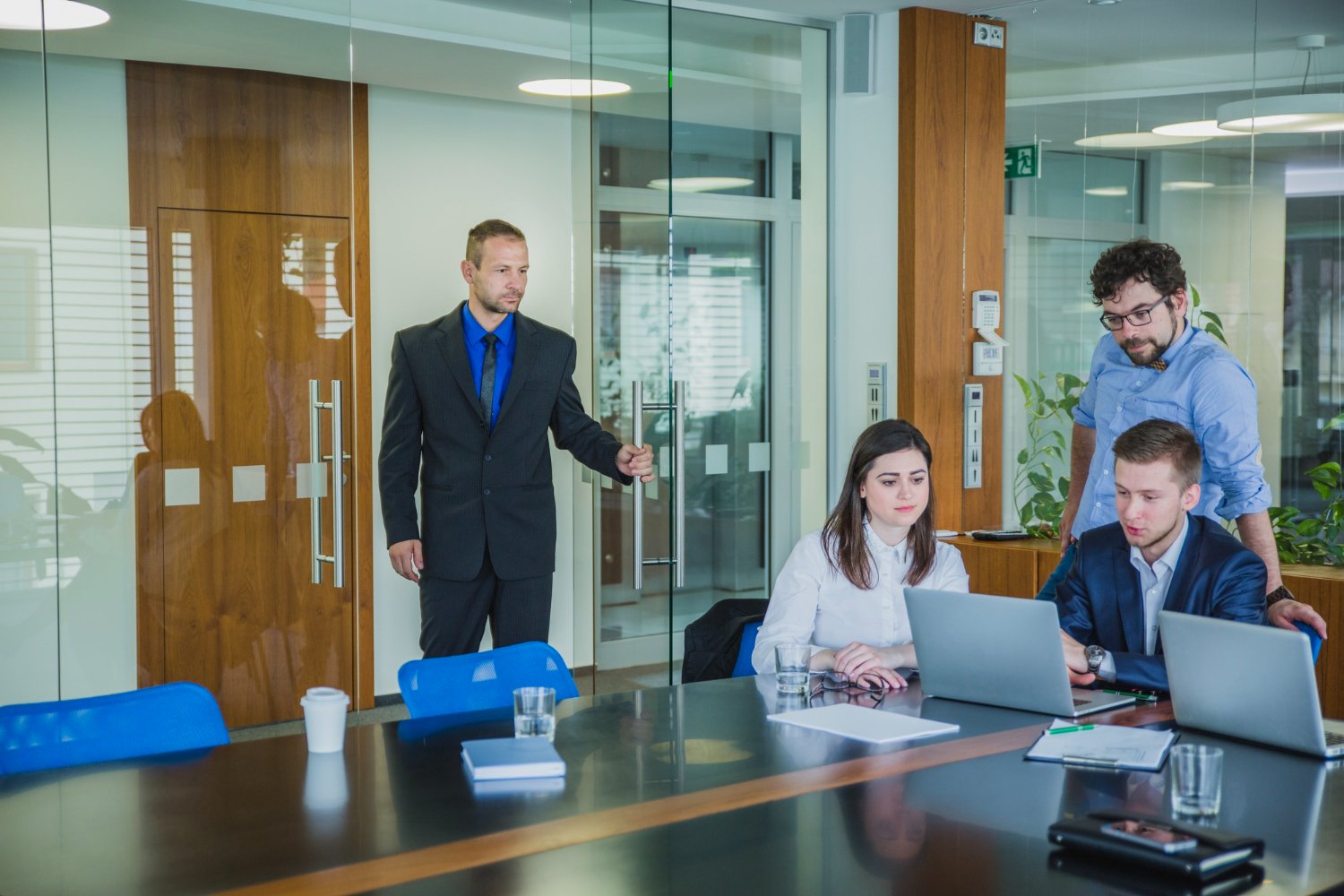 Young professional entering startup office meeting with coworkers discussing business strategy